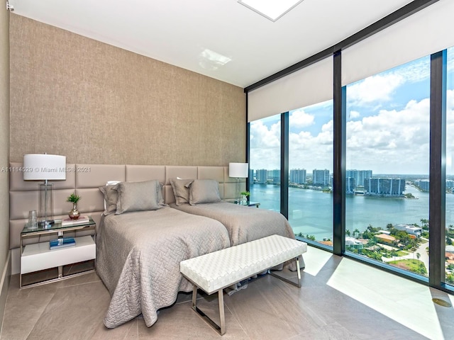 bedroom with a water view, floor to ceiling windows, and multiple windows