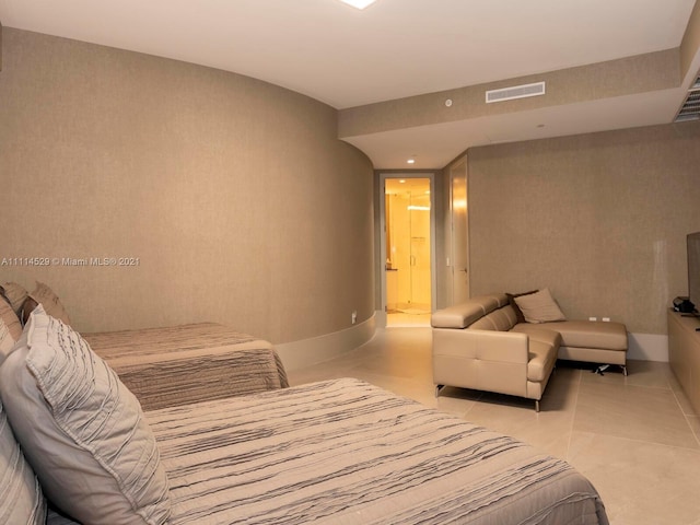 bedroom with light tile floors and ensuite bath