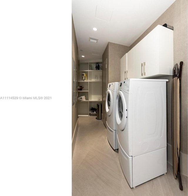 clothes washing area featuring cabinets and independent washer and dryer