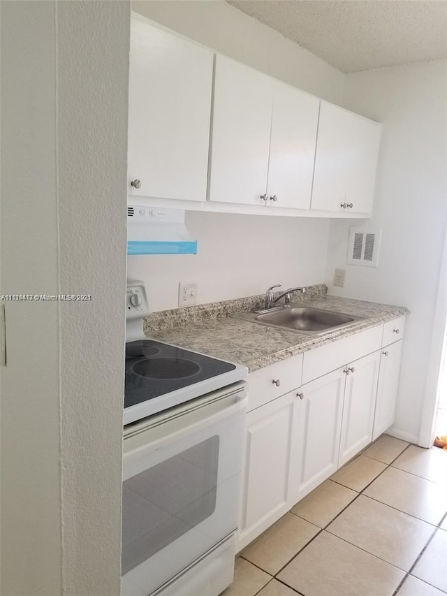 kitchen featuring sink, exhaust hood, light tile patterned floors, electric range, and white cabinets