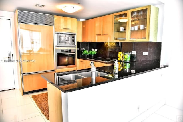 kitchen featuring light tile floors, sink, tasteful backsplash, kitchen peninsula, and built in appliances