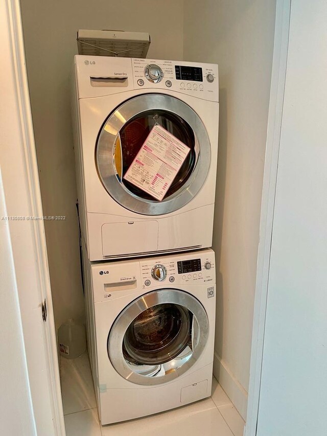 laundry area with stacked washer / dryer and light tile floors