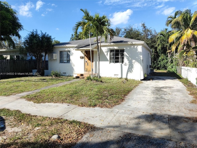 view of front of property featuring a front lawn and a wall mounted AC