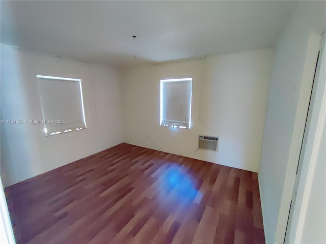 empty room featuring a wall mounted AC and dark wood-type flooring