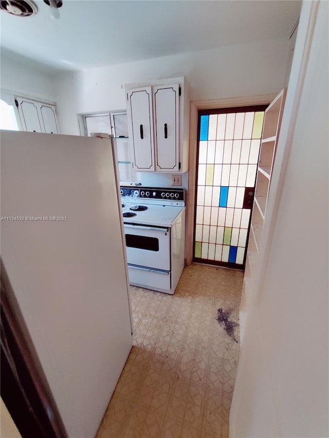 kitchen with white appliances, white cabinetry, a healthy amount of sunlight, and light tile floors