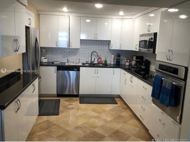 kitchen with white cabinetry, appliances with stainless steel finishes, sink, light tile floors, and tasteful backsplash