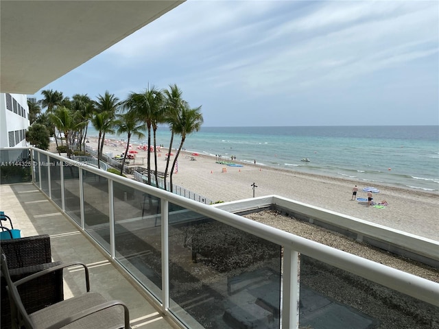 balcony with a water view and a view of the beach