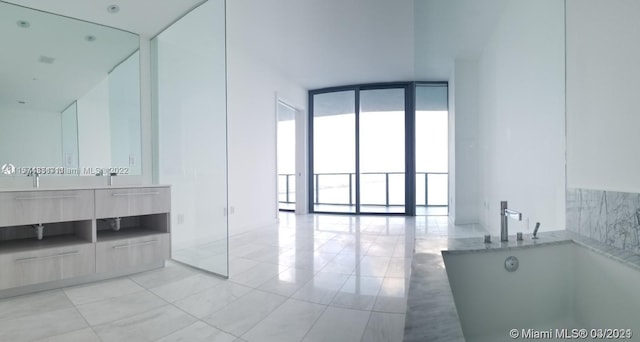 bathroom with a bath to relax in, floor to ceiling windows, tile floors, and large vanity