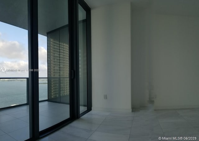 tiled empty room with floor to ceiling windows and a water view