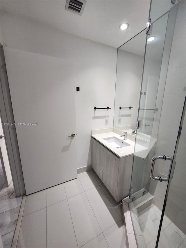 bathroom with a shower with door, vanity with extensive cabinet space, and tile flooring