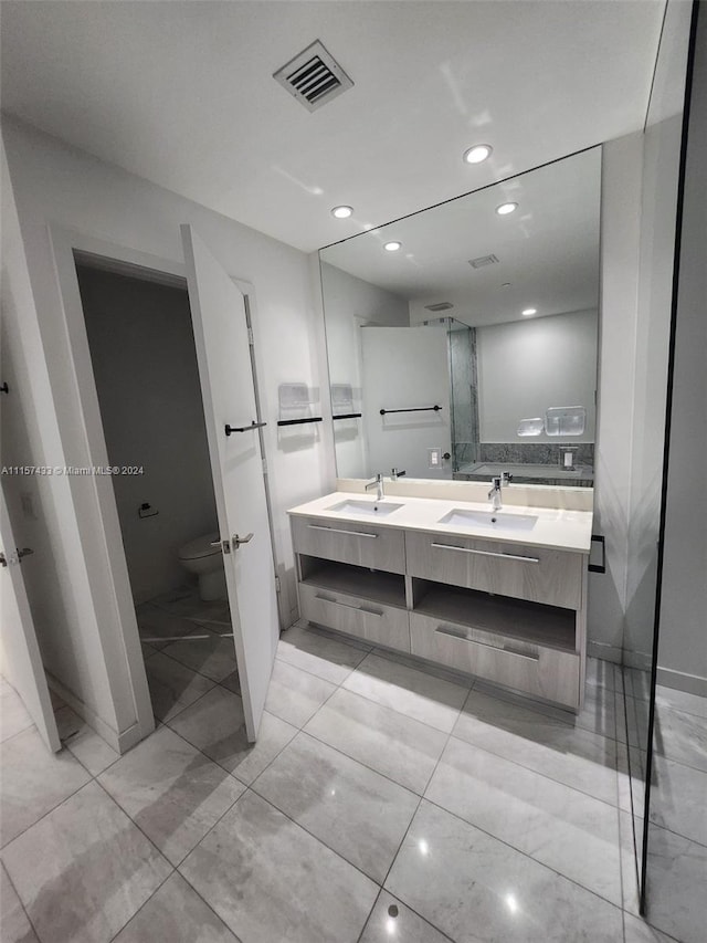 bathroom featuring double sink vanity, tile flooring, and toilet