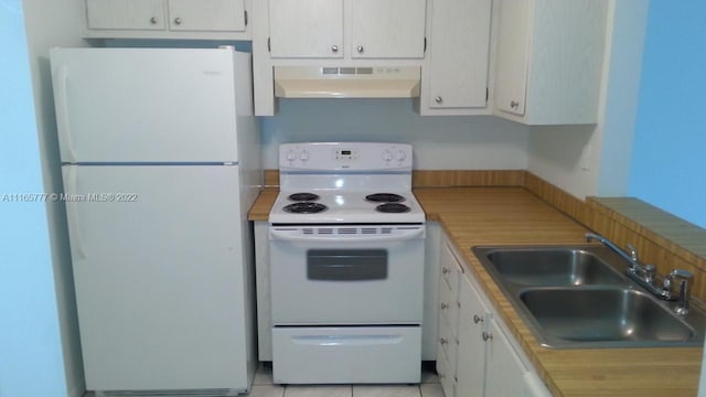 kitchen with white appliances, sink, light tile patterned floors, range hood, and white cabinetry