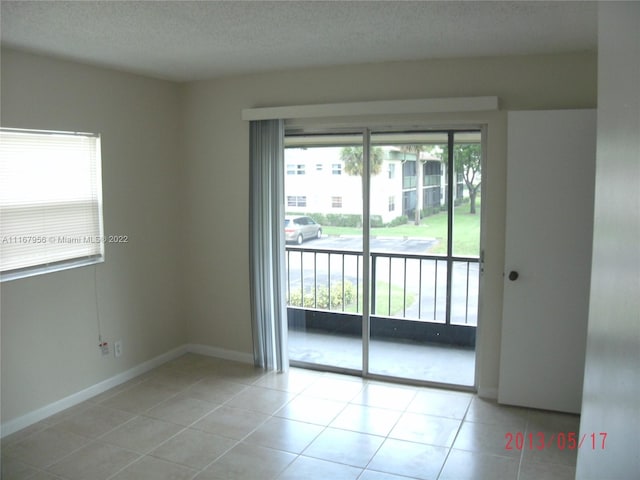 spare room featuring light tile patterned floors, a textured ceiling, and a healthy amount of sunlight