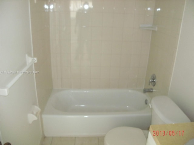 bathroom with tile patterned flooring, tiled shower / bath combo, and toilet