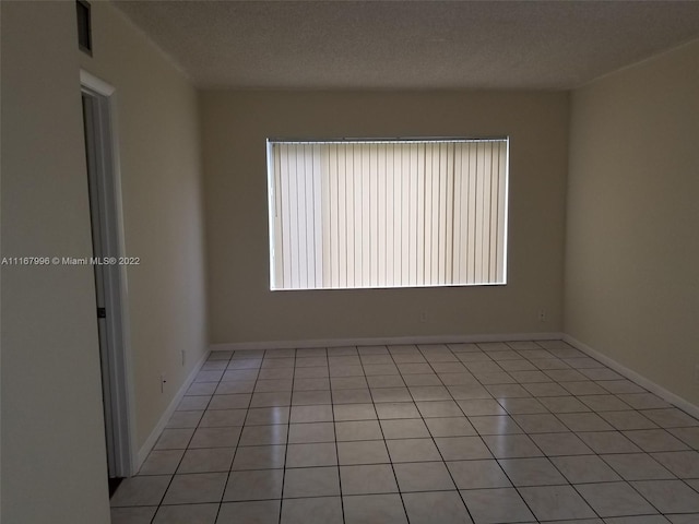 tiled empty room with a textured ceiling