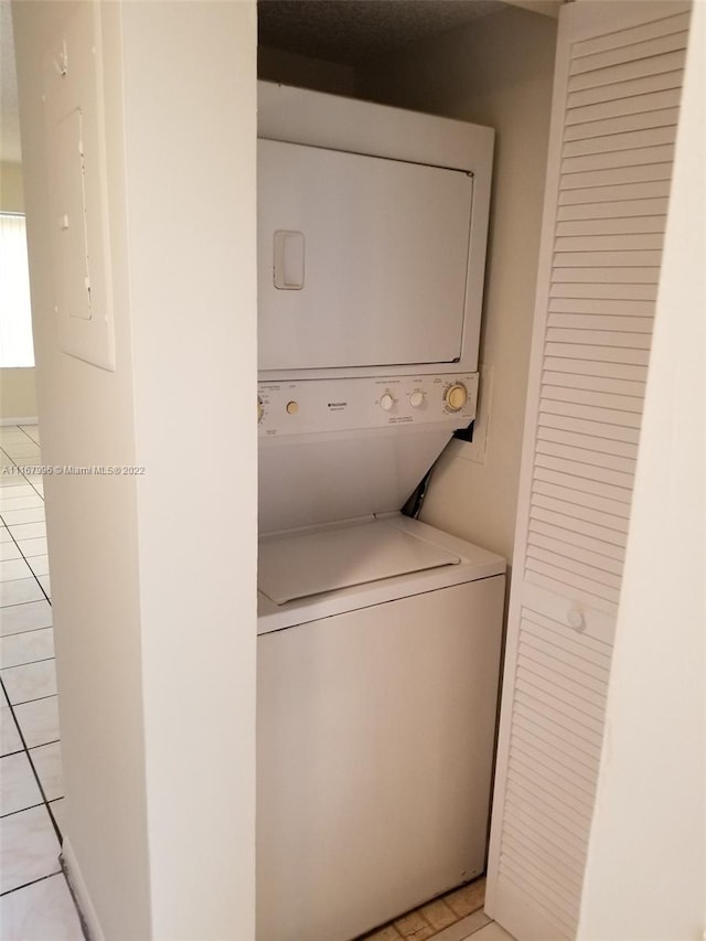 washroom with light tile patterned floors, electric panel, and stacked washer / dryer