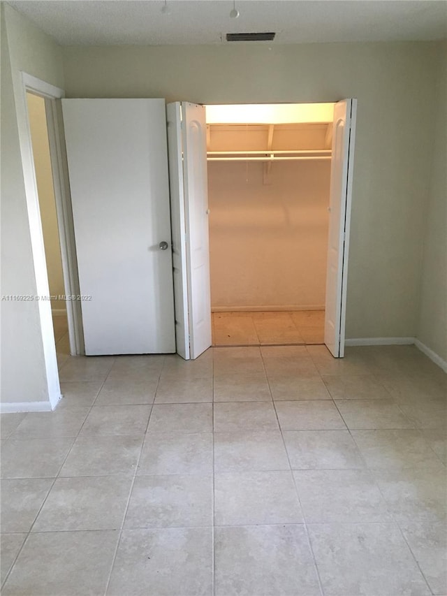 unfurnished bedroom featuring a closet and light tile patterned floors