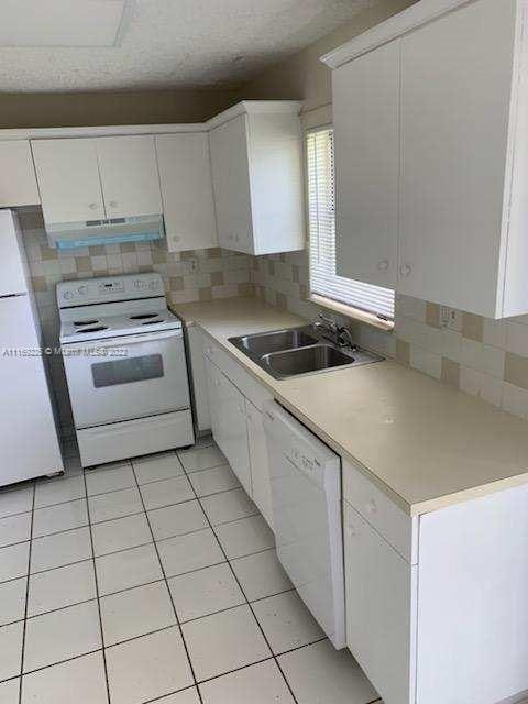 kitchen featuring white cabinets, white appliances, sink, and exhaust hood