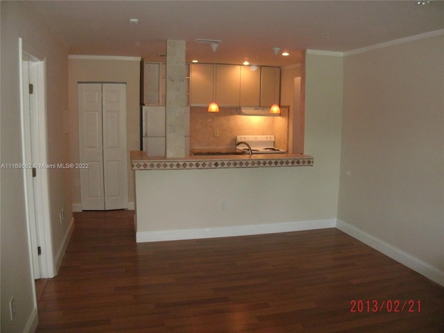 kitchen with kitchen peninsula, crown molding, dark hardwood / wood-style flooring, and white appliances