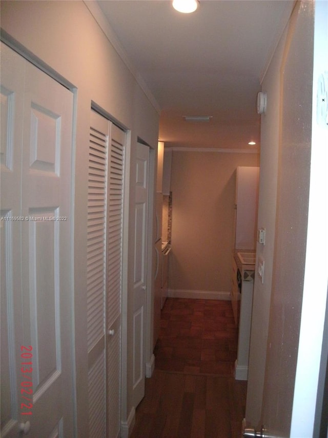 hallway with crown molding and dark wood-type flooring