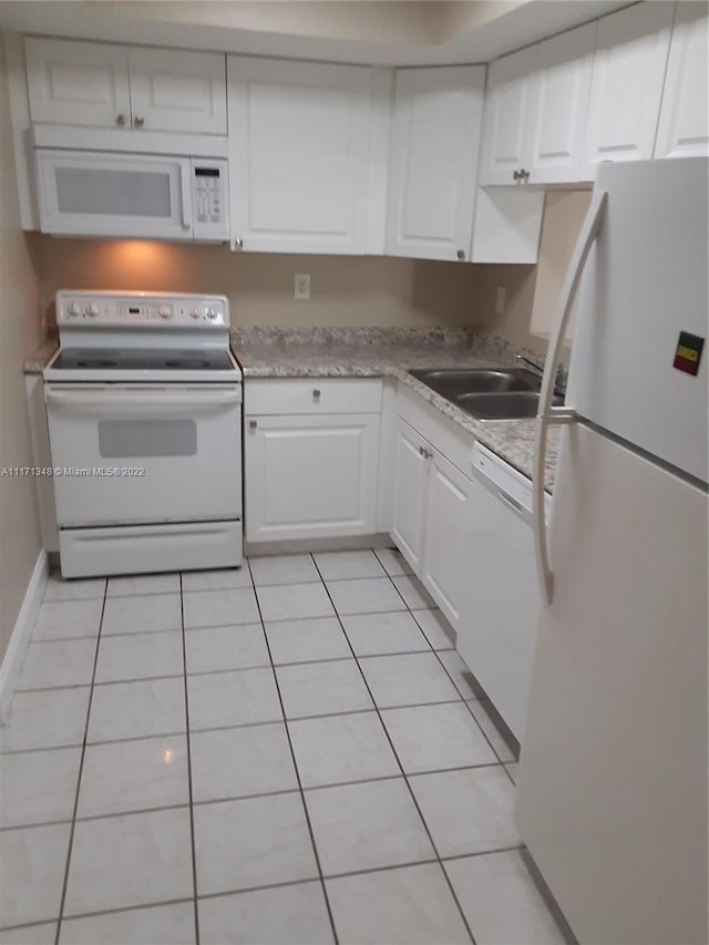 kitchen with light tile patterned floors, white cabinets, white appliances, and sink