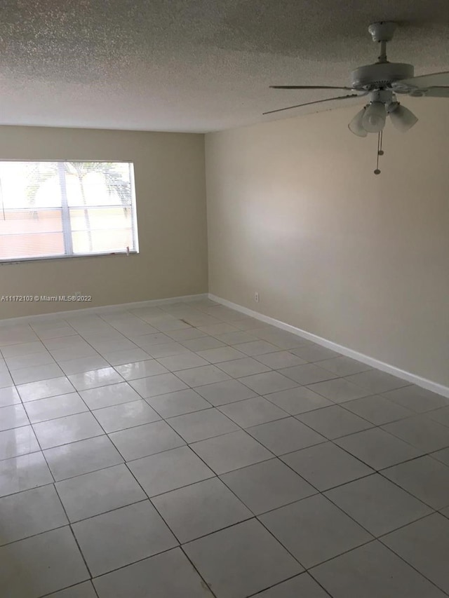 unfurnished room featuring ceiling fan, light tile patterned floors, and a textured ceiling