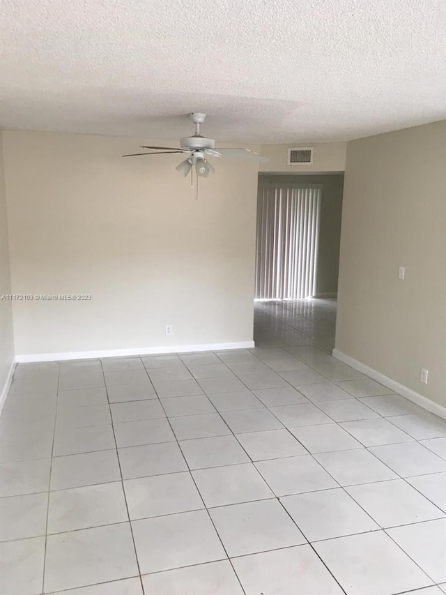 tiled empty room featuring ceiling fan and a textured ceiling