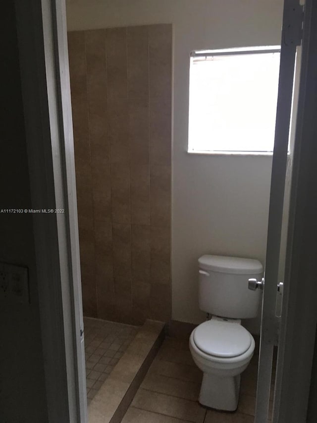 bathroom featuring tile patterned flooring, toilet, and a tile shower