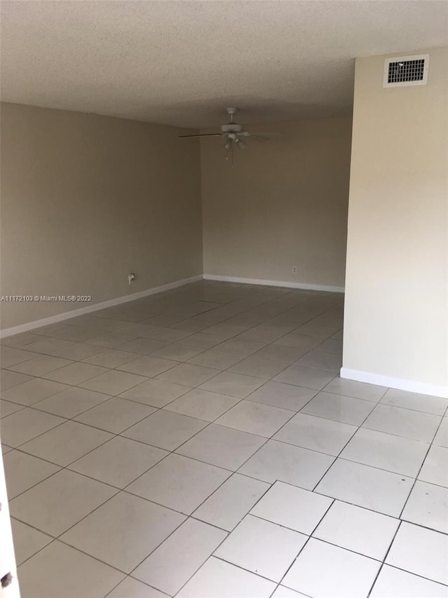 tiled spare room with ceiling fan and a textured ceiling