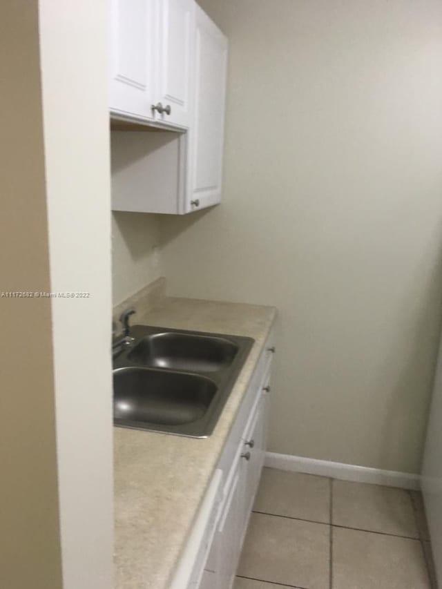 kitchen with white cabinets, light tile patterned floors, and sink