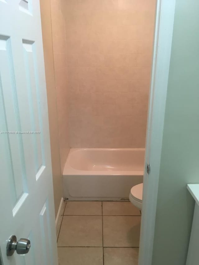 bathroom with tile patterned flooring, tiled shower / bath combo, and toilet