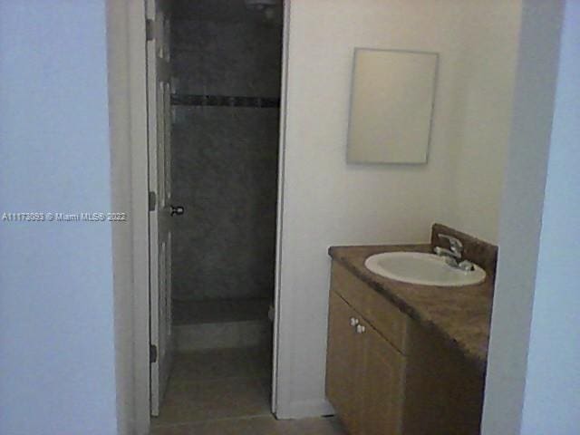 bathroom featuring a tile shower, tile patterned floors, and vanity