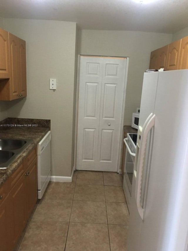 kitchen with white appliances, sink, and light tile patterned floors