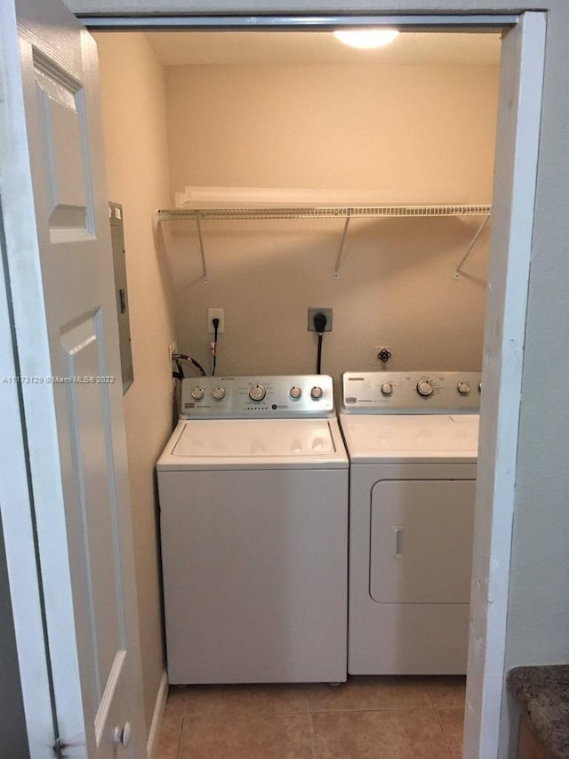 clothes washing area with light tile patterned floors, electric panel, and washing machine and clothes dryer