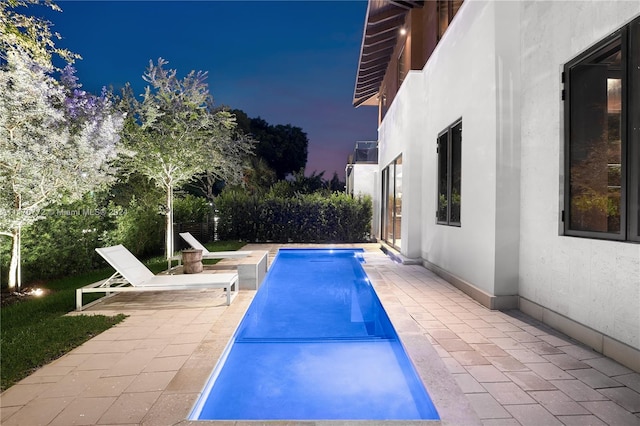 pool at twilight featuring a patio