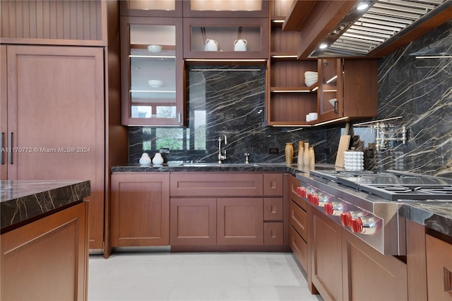 kitchen with dark stone countertops, sink, extractor fan, and tasteful backsplash