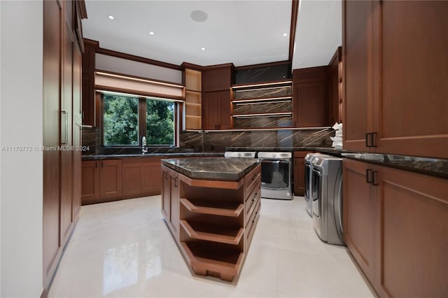 kitchen with dark stone counters, crown molding, stainless steel oven, and tasteful backsplash