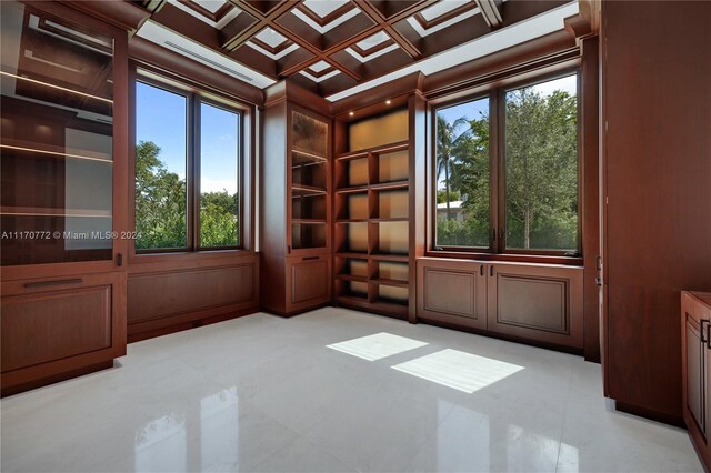 empty room with wooden walls, a healthy amount of sunlight, coffered ceiling, and ornamental molding