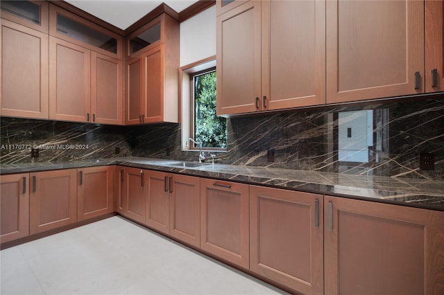 kitchen featuring decorative backsplash, dark stone countertops, and sink