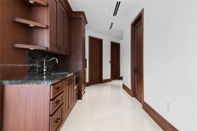 kitchen with dark stone counters, backsplash, and sink