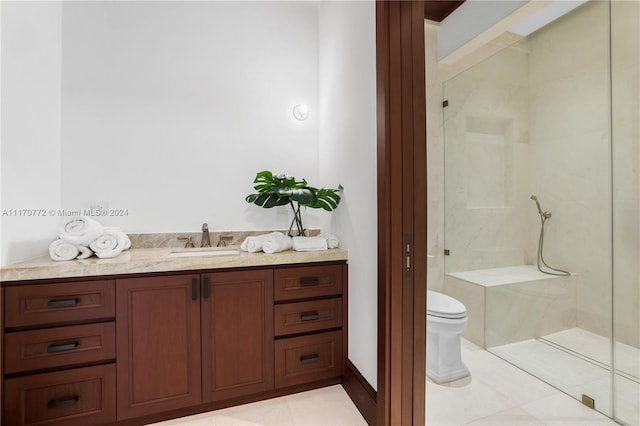 bathroom with tile patterned flooring, tiled shower, vanity, and toilet