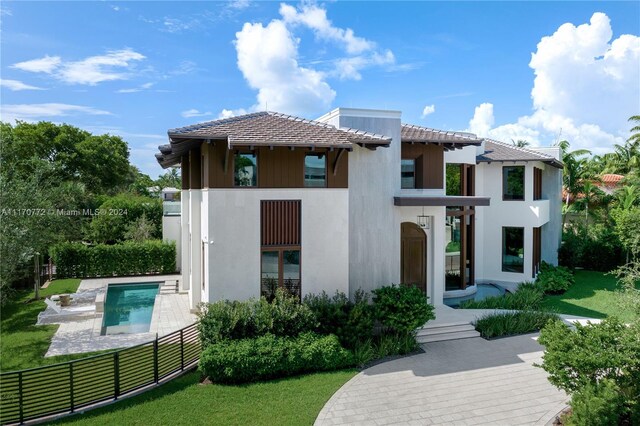 rear view of property with a balcony, a lawn, a patio, and a fenced in pool