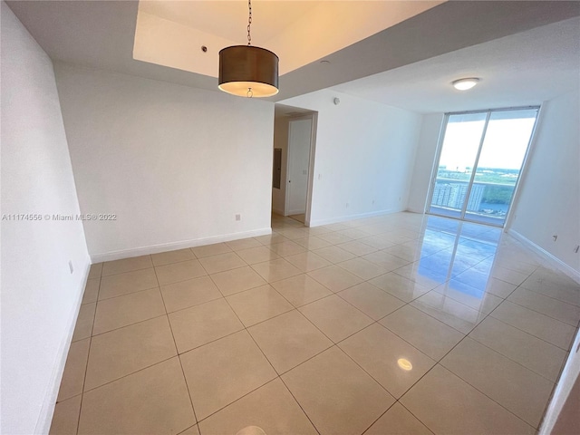 empty room with expansive windows and light tile flooring