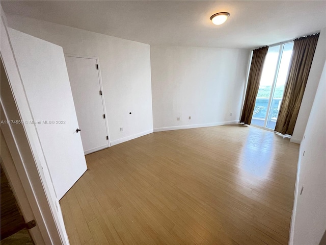 empty room with floor to ceiling windows and light wood-type flooring