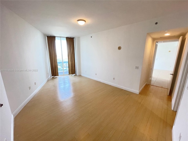 unfurnished room featuring a wall of windows and light wood-type flooring