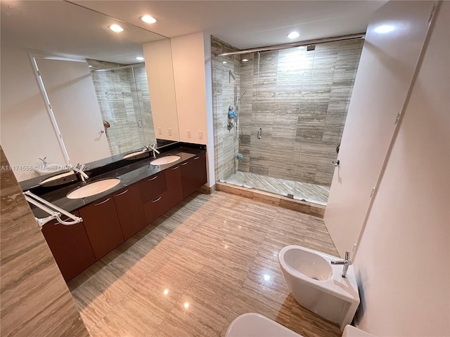 bathroom featuring vanity with extensive cabinet space, dual sinks, a shower with shower door, and a bidet