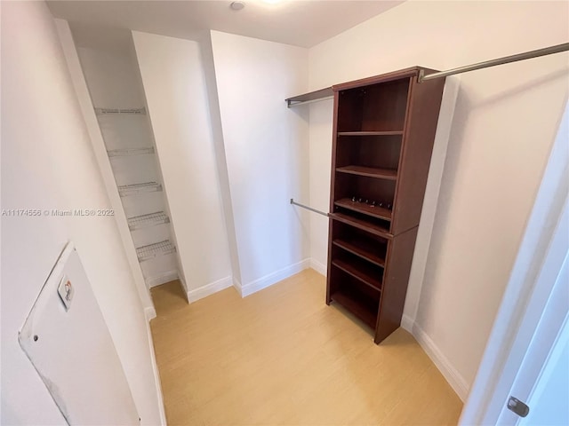 walk in closet with light hardwood / wood-style flooring