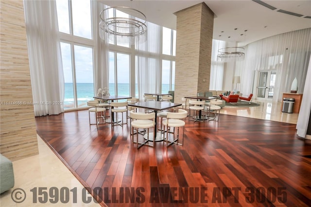 dining room featuring a water view, a notable chandelier, a towering ceiling, and plenty of natural light