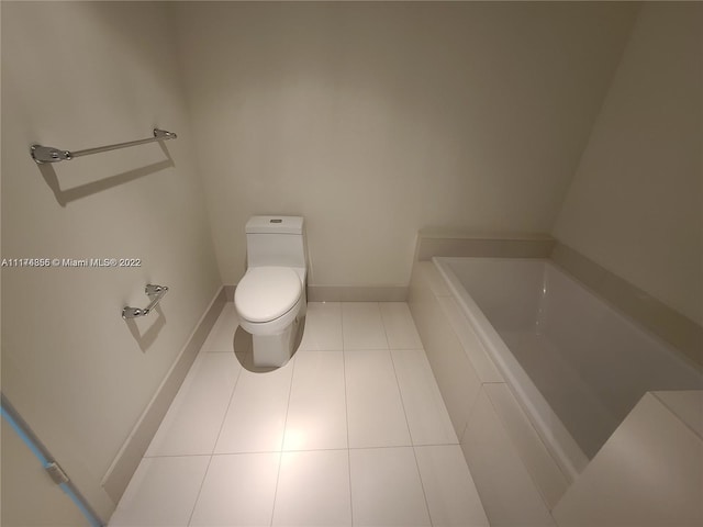 bathroom featuring toilet, a washtub, and tile floors