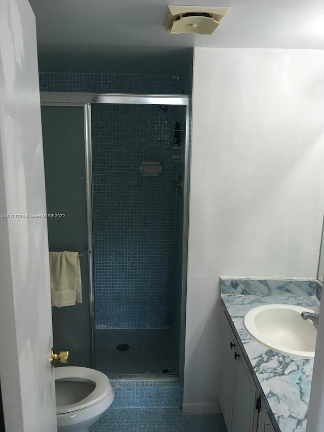 bathroom with tile patterned floors, vanity, toilet, and walk in shower